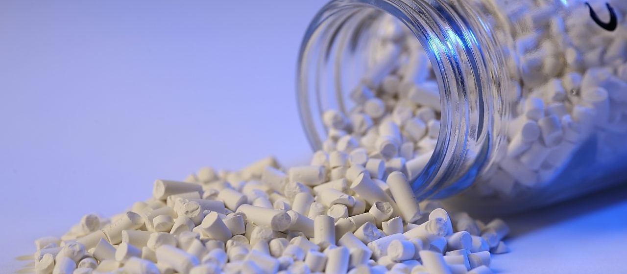 Catalyst product pouring out of a tipped glass bottle